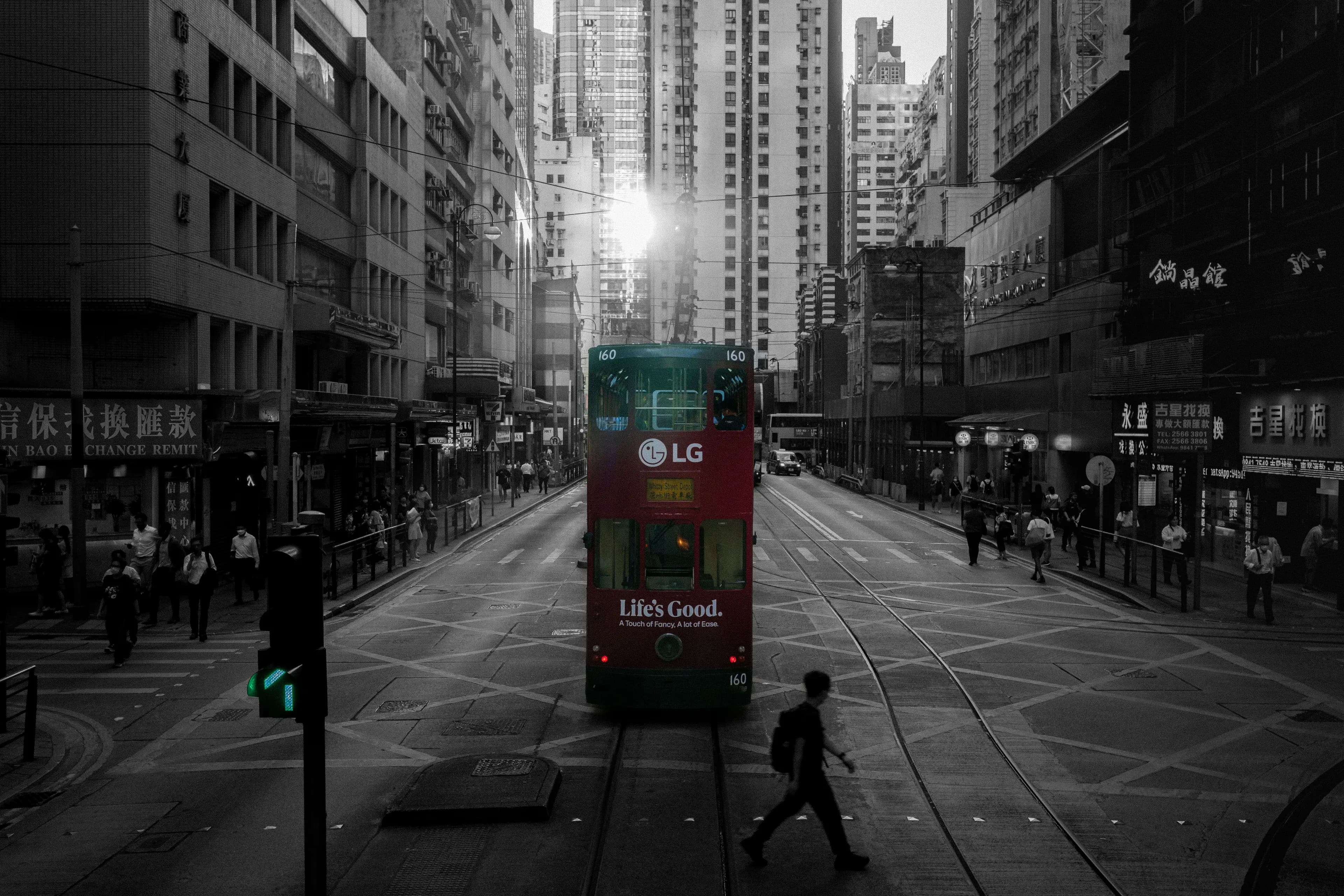 A red tram moving through a dense Hong Kong street